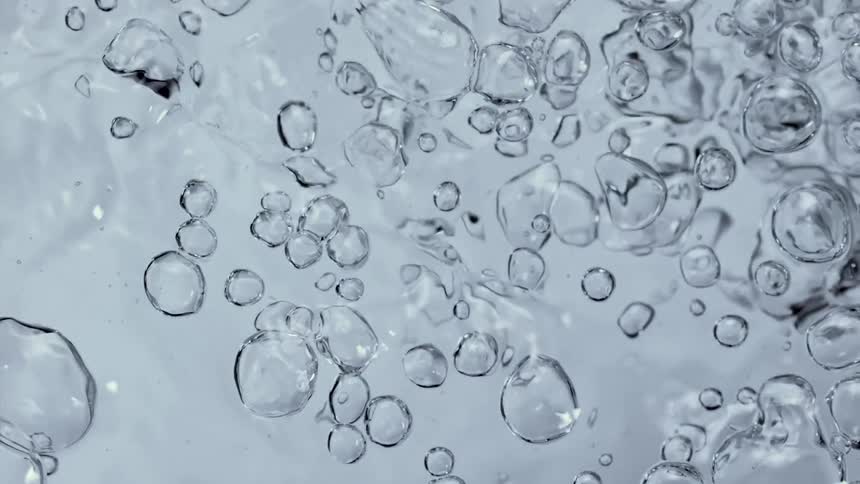 Air bubbles breaking the surface of a pool of clear translucent water