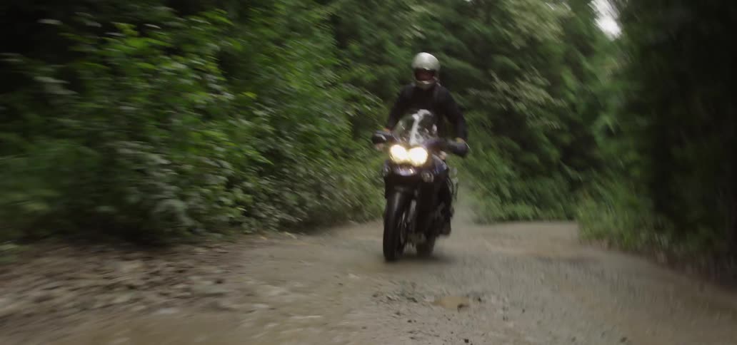 A person rides a motorcycle on a muddy road