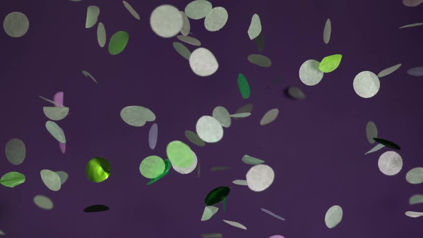 Confetti of different colors is dropping in front of a purple background