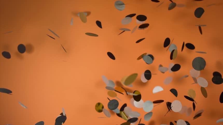 Round confetti falling in front of an orange background
