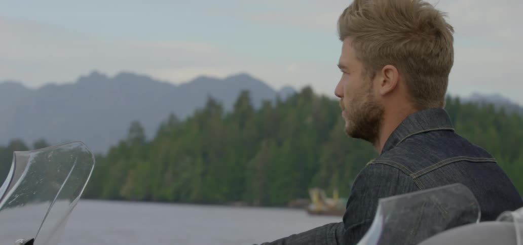 A man gazing out over the water as he sits in a boat on a windy, chilly day
