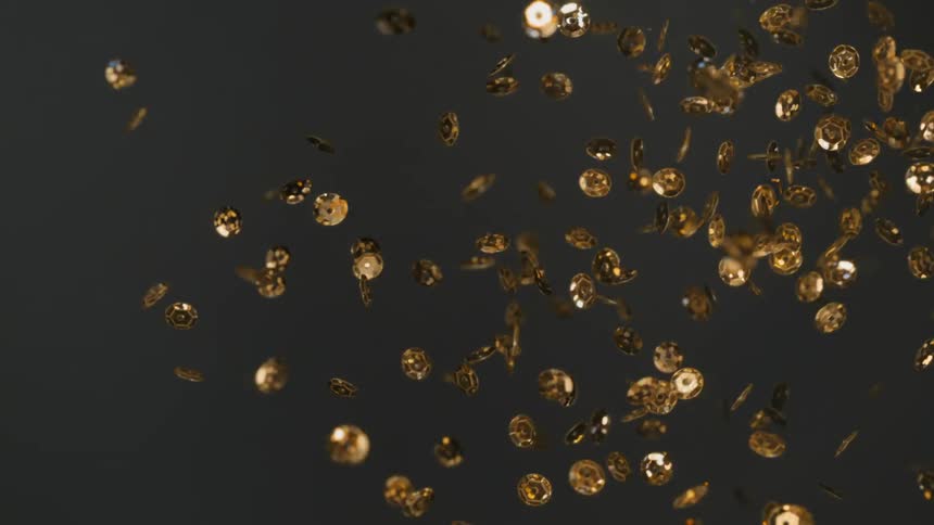 Coin shaped pieces of gold confetti float in the air
