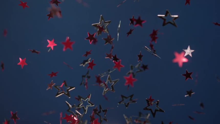 Red and silver stars shine and reflect light as they fly into the air twisting and turning as they fall back down