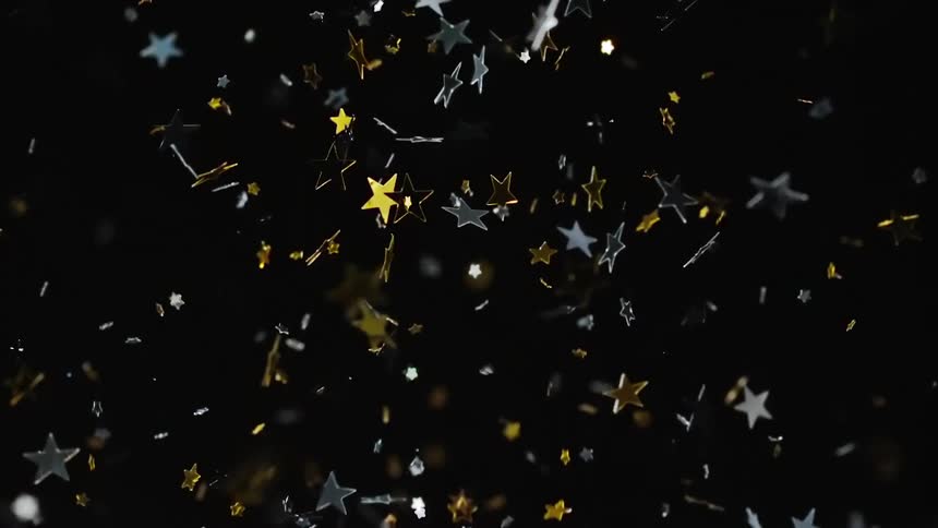 Gold and silver stars shine and reflect light as they fall from the air twisting and turning as they fly back up