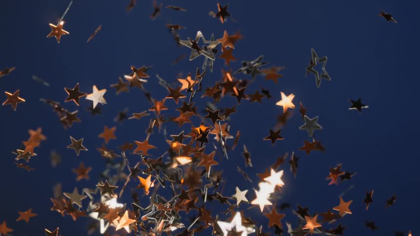 Gold and silver stars twist and shine as they float in the air reflecting light