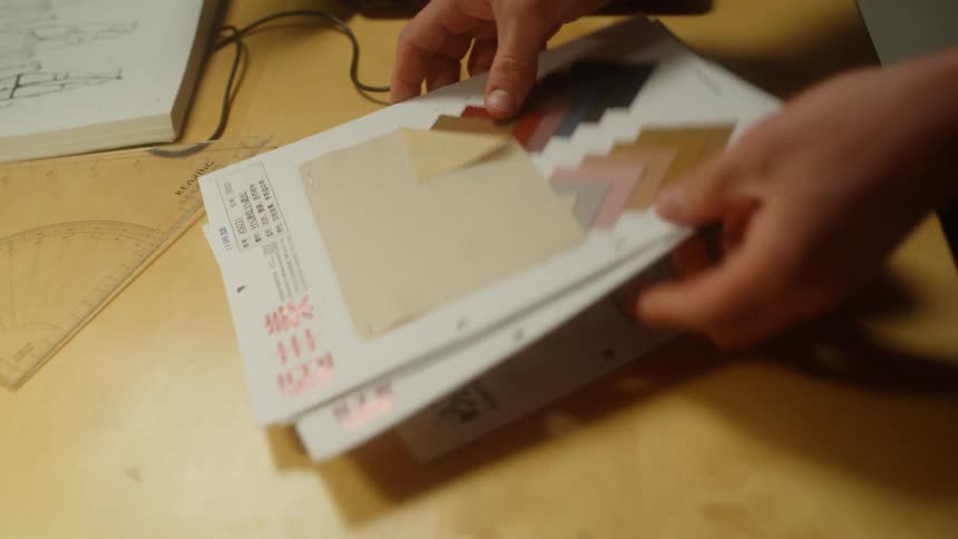 A man flips through fabric swatches at his desk