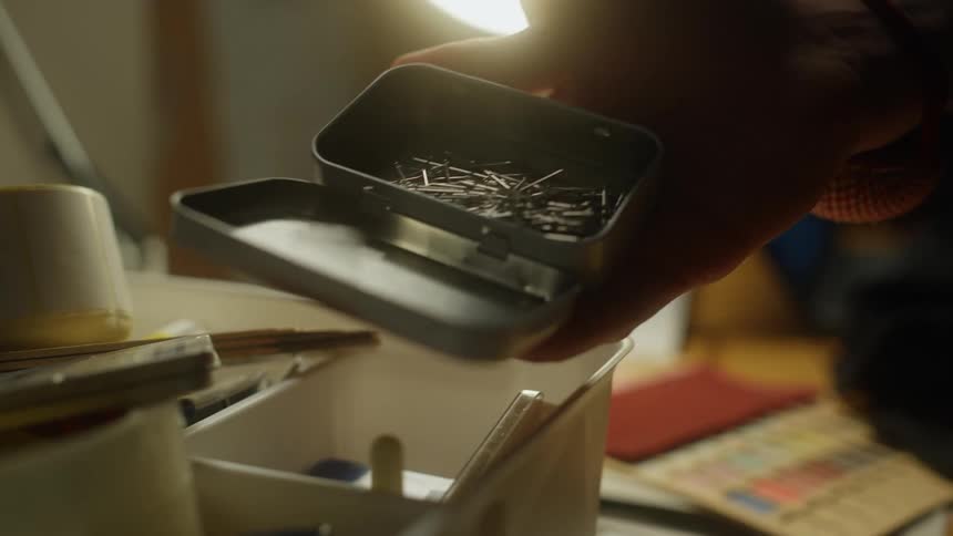 A person is taking nails from the small box