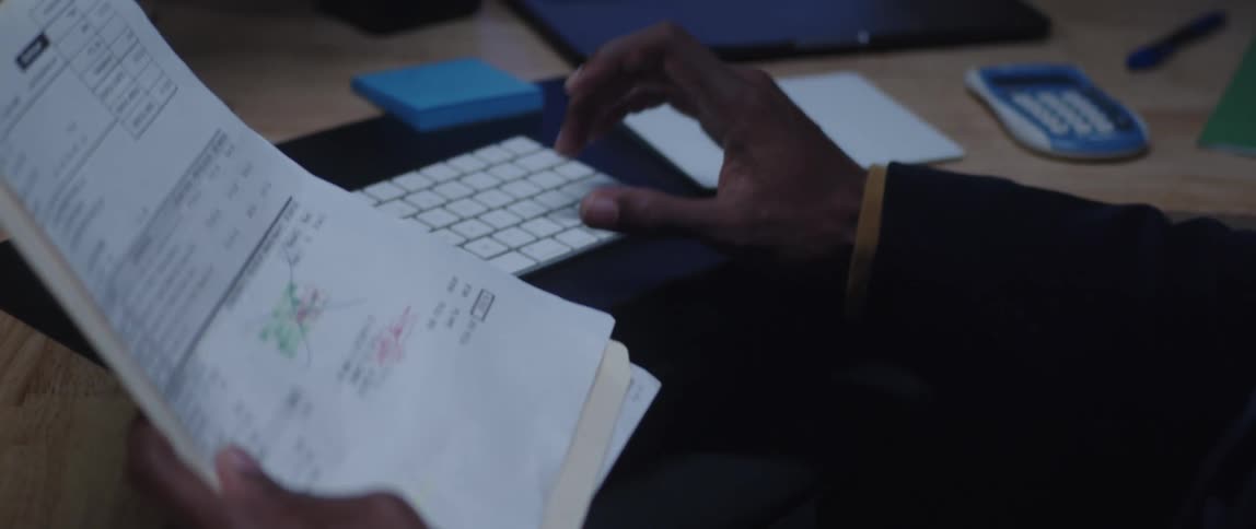 A man enters data from a piece of paper into his computer