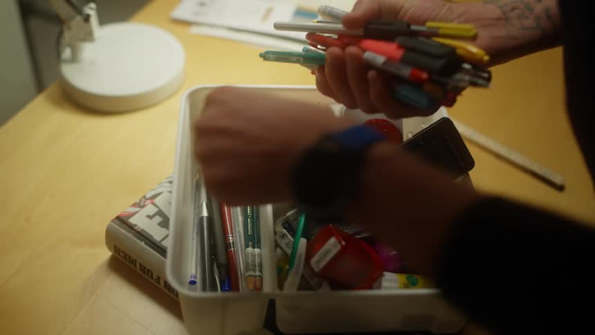 A man rummages through an organizer filled with paint brushes