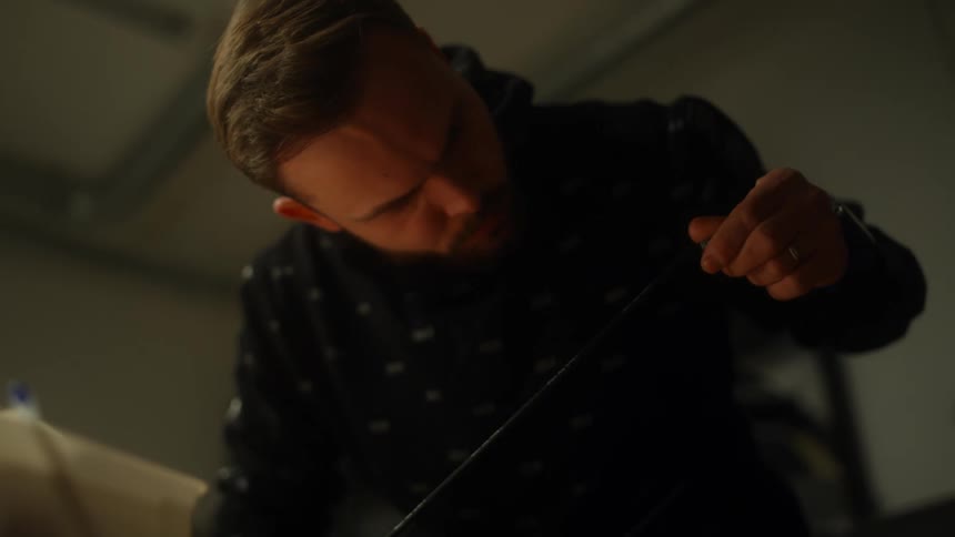 A man at home examines a piece of clothing and pulls a string on it