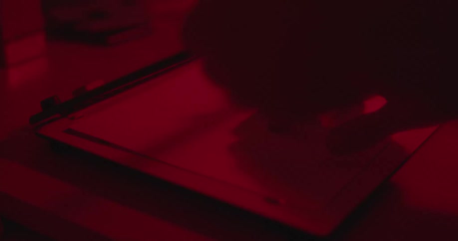 A man places a photo sheet on a cutter in a darkroom