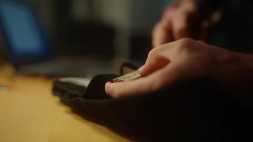Close up of tailors hands measuring black shirt in tailors store
