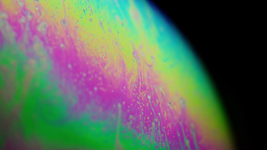 Fluorescent colors move down on the surface of a sphere as it drips and blends in an organic manner