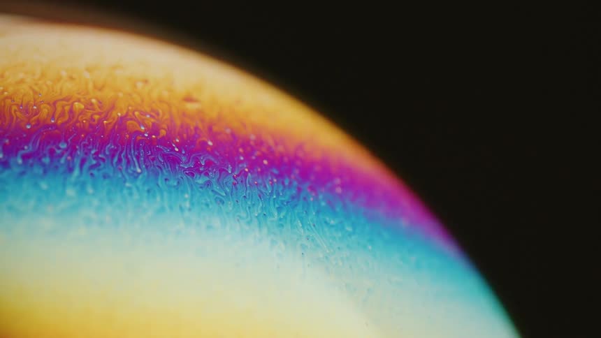 Fluorescent colors move down on the surface of a sphere as it drips and blends in an organic manner