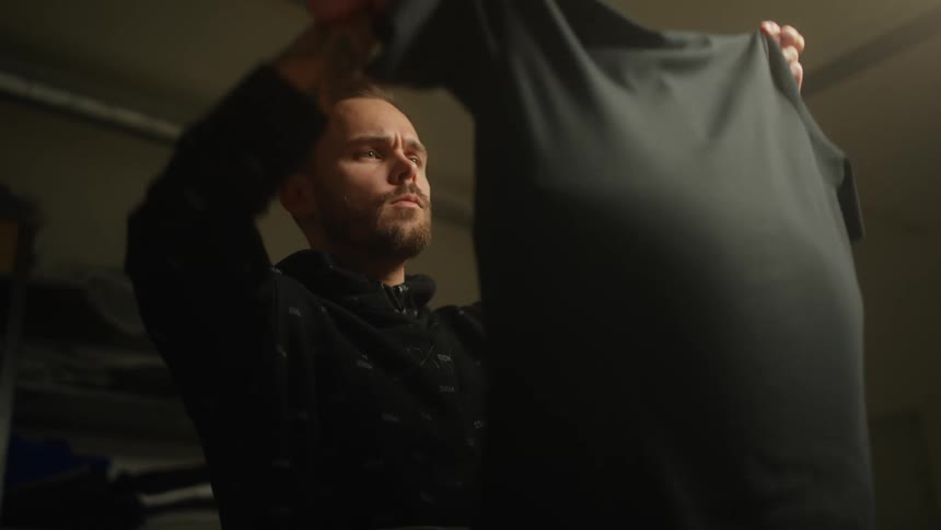 Male designer with pincushion on his wrist removes shirt from manikin