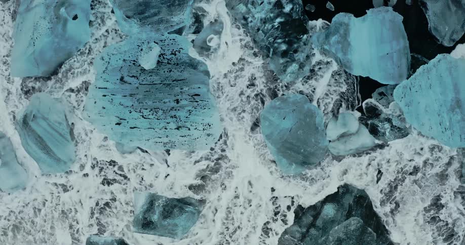 Ocean waves crashing into chunks of ice on a shoreline