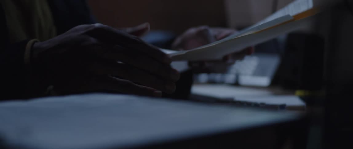 Man looks through folder while sitting at desk with computer