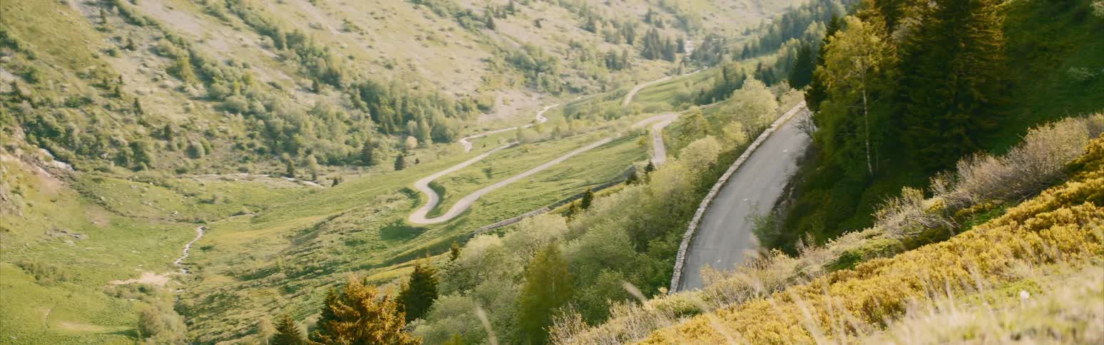 A windy road runs through a grassy field and up a hill