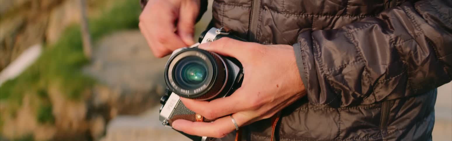 A man winds film in to a camera outside