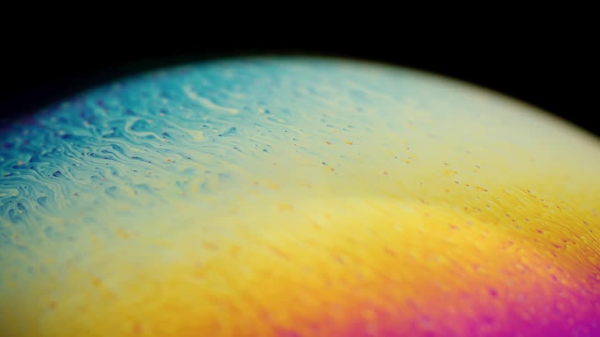 The surface of a soapy bubble reveals an array of beautiful colors