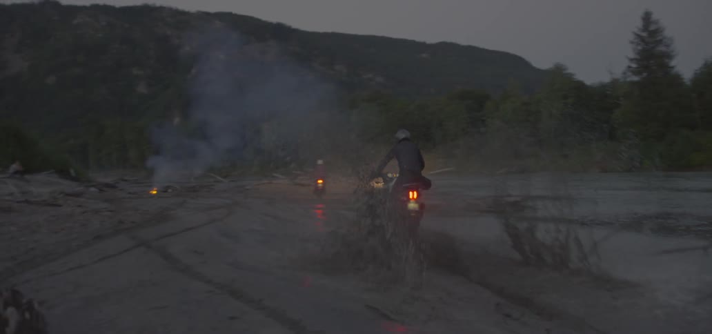 People drive bikes across a mud hole