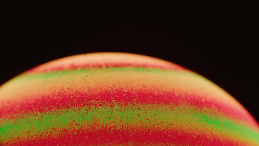 Fluorescent pink and green lines of liquid swirl in a sphere