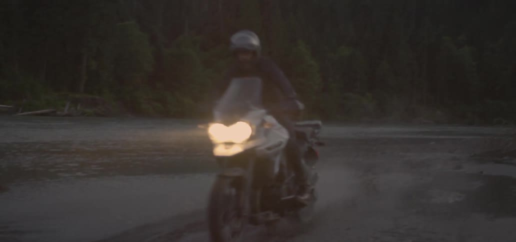 A person rides their motorcycle over some snow