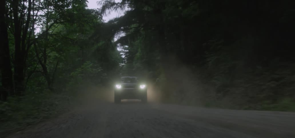 Vehicles ascend a dirt mountain road through the fog