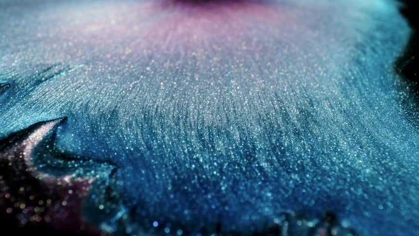 A liquid with a large amount of blue glitter suspended in it flows outward from a central point