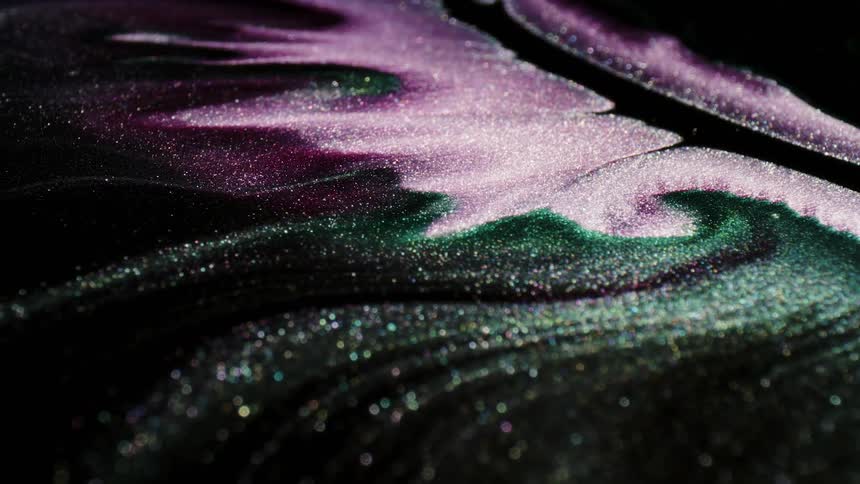 A dark and viscous liquid has swirls of purple and glittering particles in it as it flows by
