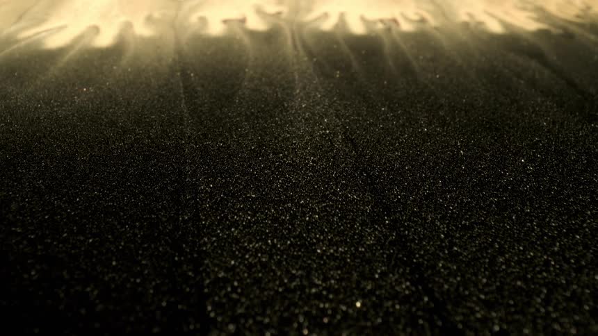 Fingers of gold glitter spread and dissolve in black