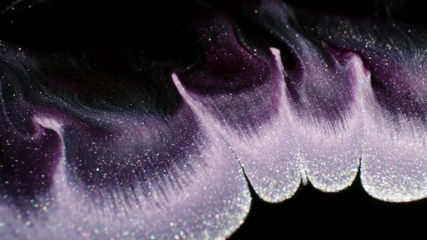 A dark fluid has a wave of suspended sparkling glitter mixing through it