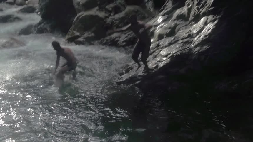 Two men jump into a rapid flowing river