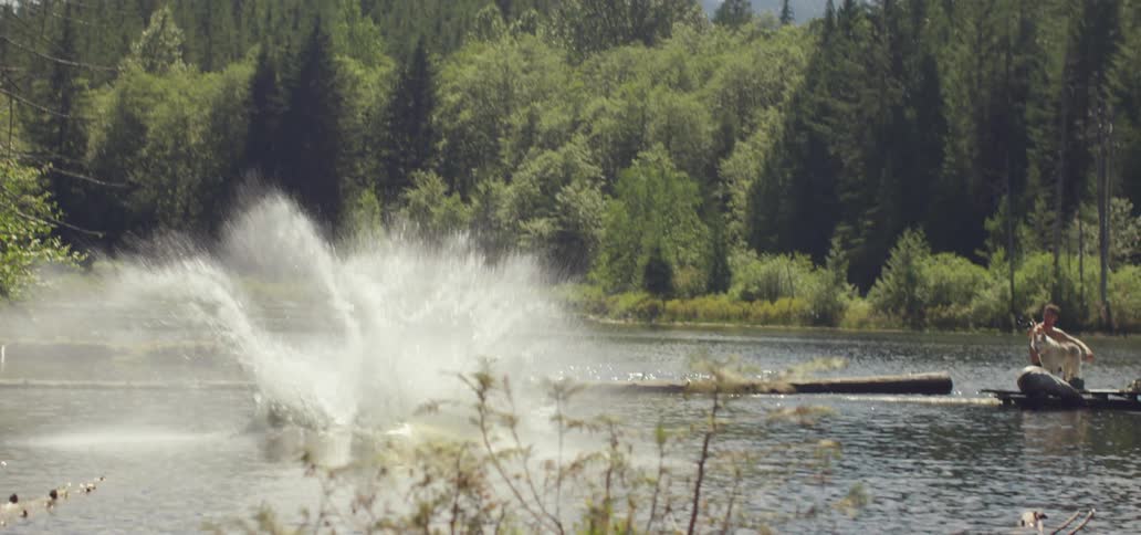 Person jumping into a lake while performing a back flip from high above