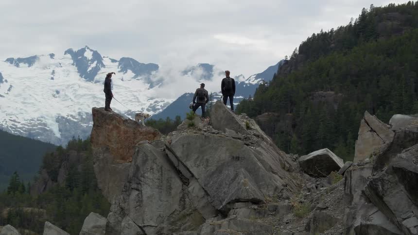 Three people standing high atop very pointy rocks and one has a dog