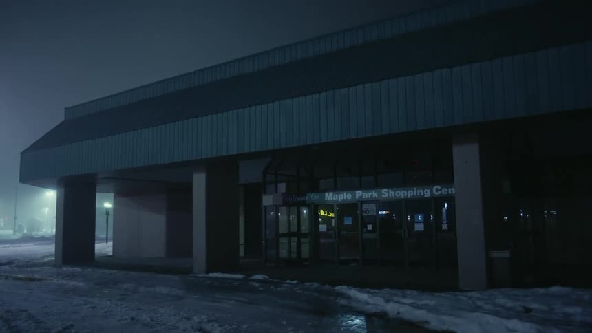 The facade of a closed shopping center on a winter night
