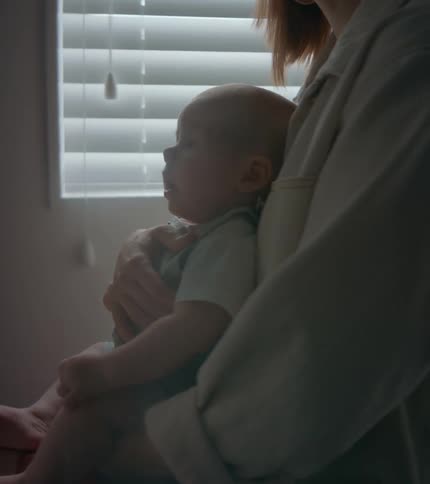 A woman holds her baby in her lap while the child sneezes