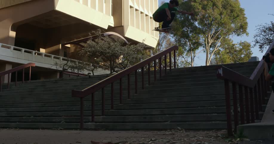 Man trying skateboard jump down outdoor steps falls as another uses camera