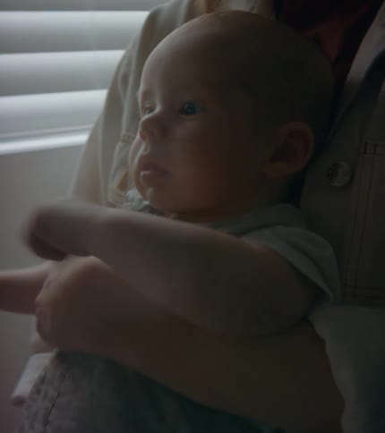 A baby in an adults arms squirming and smirking