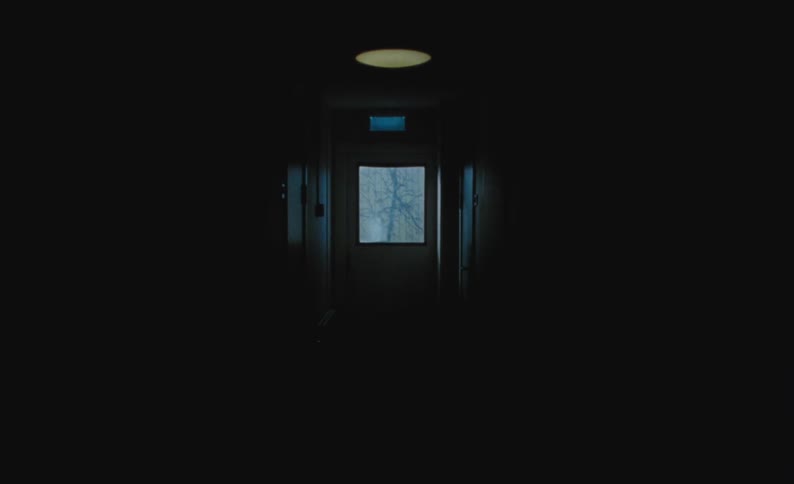 A dark hallway with a door leading to the outdoors