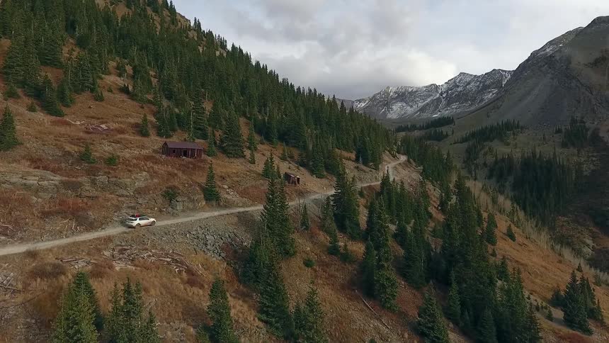 A vehicle loaded with gear drives along a very narrow mountain road
