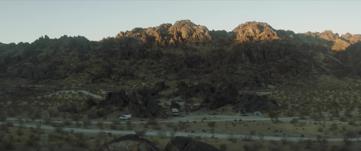 A tent set up next to vehicles in front of hills