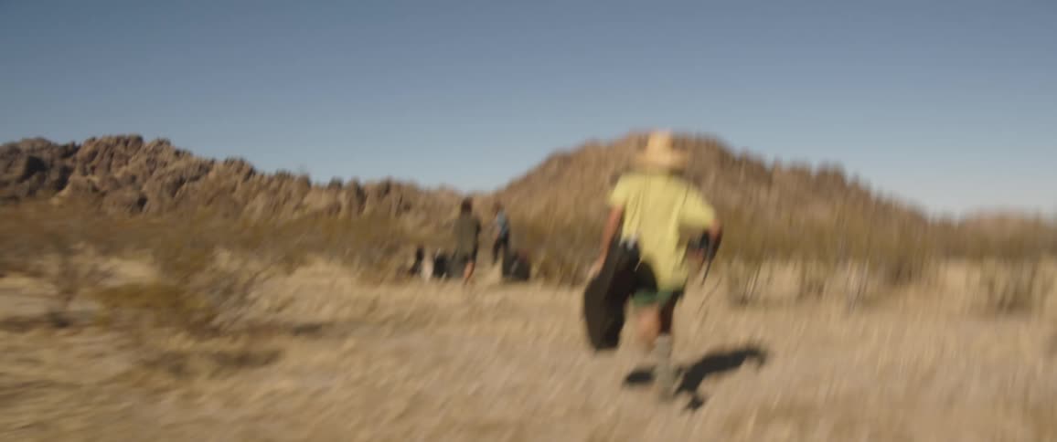 A man camping runs towards his friends