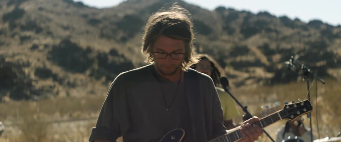 A band plays in the field below a canyon