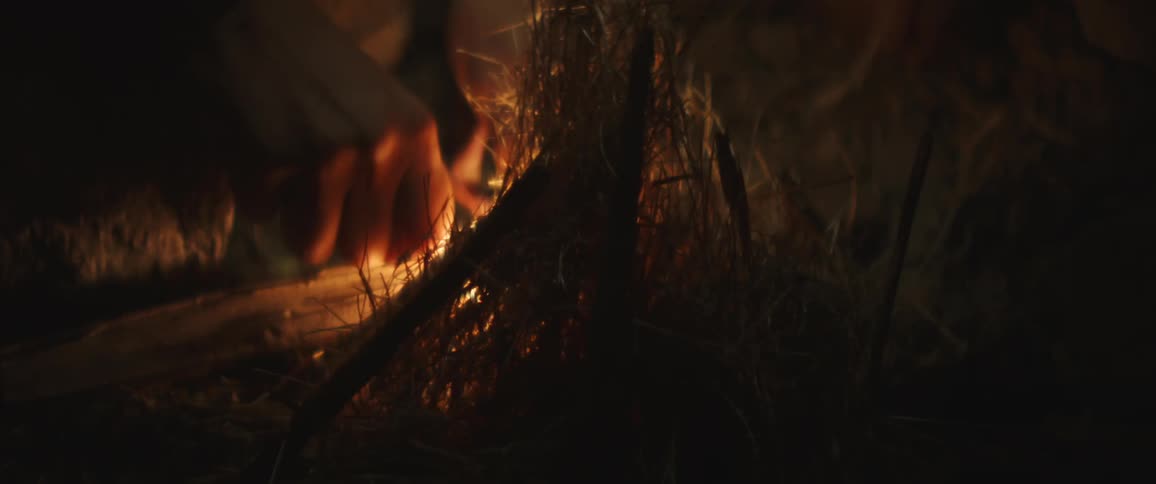 A person trying to spark a fire that theyve built up
