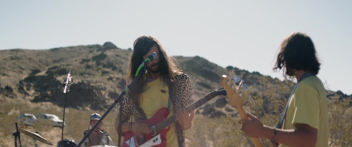 A band is playing outside in the desert near a mountain
