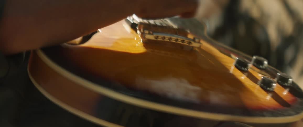 A handheld close-up shot of a man playing guitar outdoors