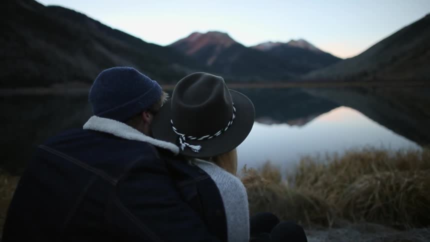 A man and woman hug each other by a lake