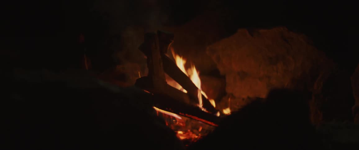 Asmall campfire with a few smaller sticks on it burning