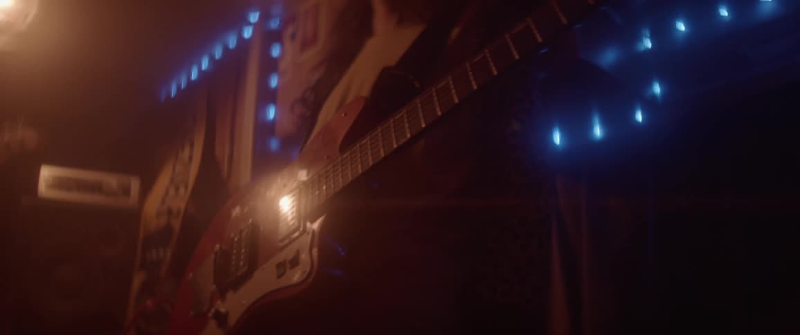 Light shines on a man on stage playing his electric guitar